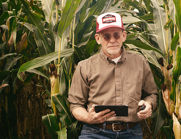 an old farmer holding an electronic tablet on a farm