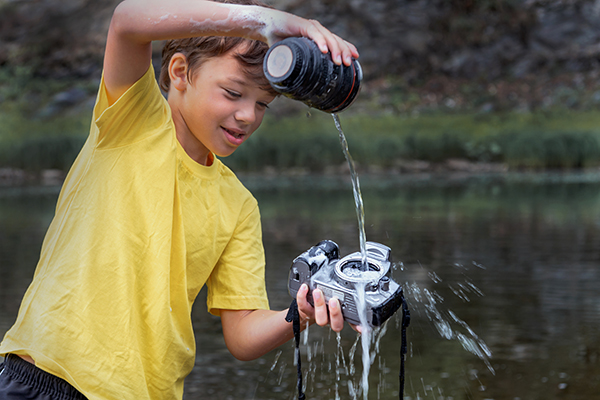 a child pouring water onto a camera